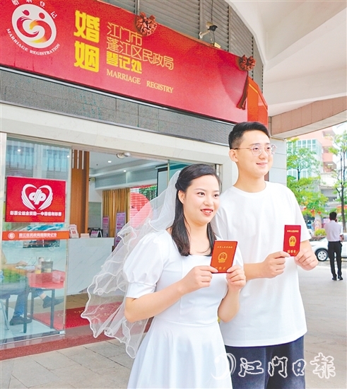 一對(duì)新人在蓬江區(qū)民政局婚姻登記處門口合影留念。
