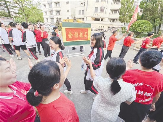 臺山一中在送考路上設(shè)置了“金榜題名”大字帖，教師身穿紅衣與學生擊掌，為學生加油。