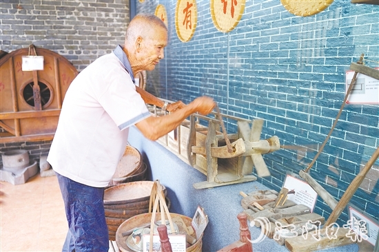 新華村打造農(nóng)耕文化展館，留住鄉(xiāng)村記憶。圖為村中老人向記者介紹農(nóng)具。