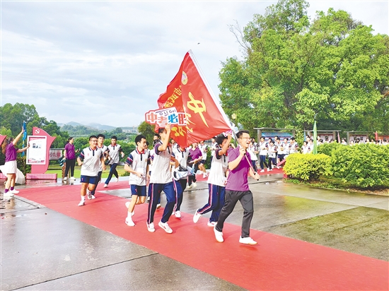 在臺山市武溪中學(xué)，老師揮舞著“中考加油”的紅旗為考生加油助威。