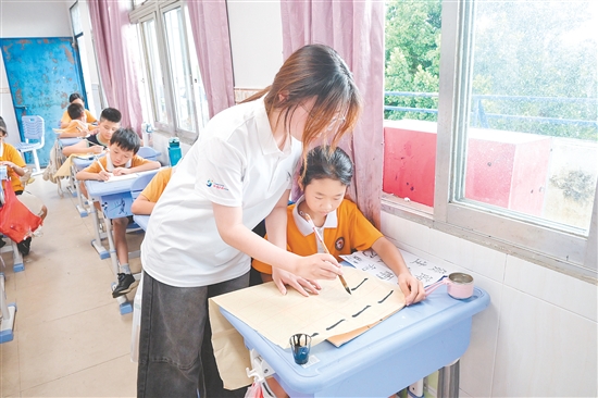 社會實踐隊隊員指導(dǎo)學(xué)生練習(xí)硬筆、軟筆書法。