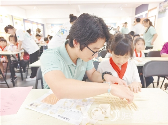 學(xué)生志愿者耐心教導(dǎo)孩子制作手工。