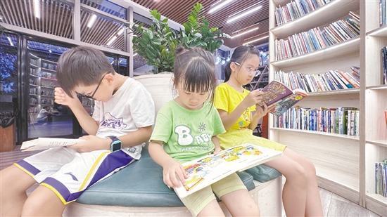 低年級(jí)學(xué)生圍坐在書(shū)架旁閱讀繪本。