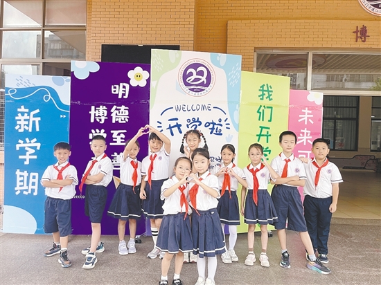 開學首日，農(nóng)林雙朗小學的學生們在學校精心準備的背景板前留影。