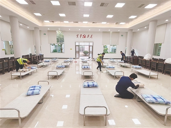 工作人員正在臨時(shí)庇護(hù)場所鋪設(shè)床位。