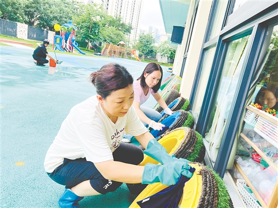 蓬江區(qū)實(shí)驗(yàn)幼兒園的老師們把教學(xué)道具輪胎放在避雨處，并清理積水。