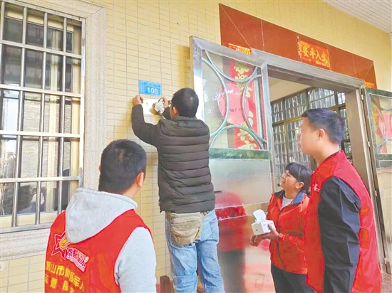 服務(wù)站工作人員細(xì)心地將“光榮之家”牌匾安裝到位。
