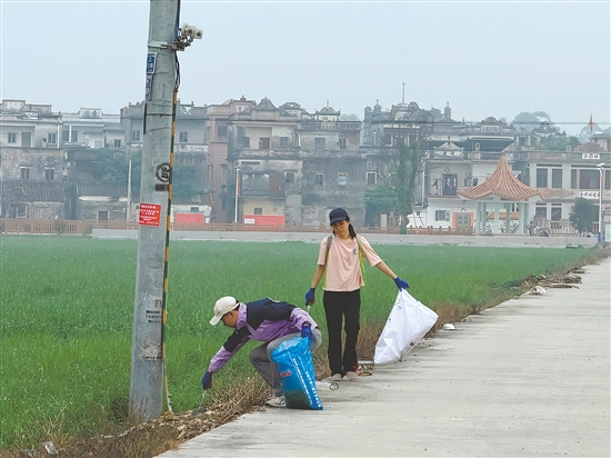 新村民走在鄉(xiāng)村道路清理垃圾。