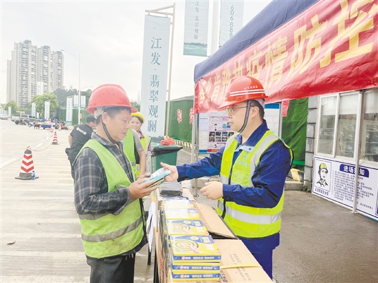 工地施工人員排隊領(lǐng)取防蚊用品。